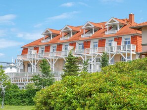 A multi-story hotel with balconies, a garden area, and a clear sky.