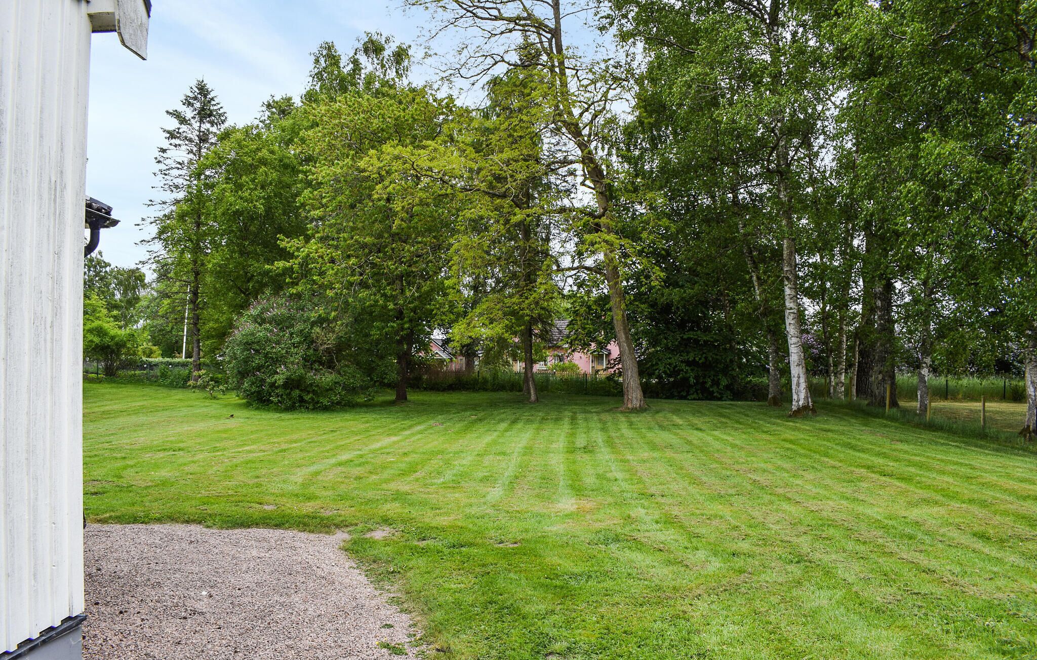 Une pelouse bien entretenue, avec des arbres et un bâtiment en arrière-plan.