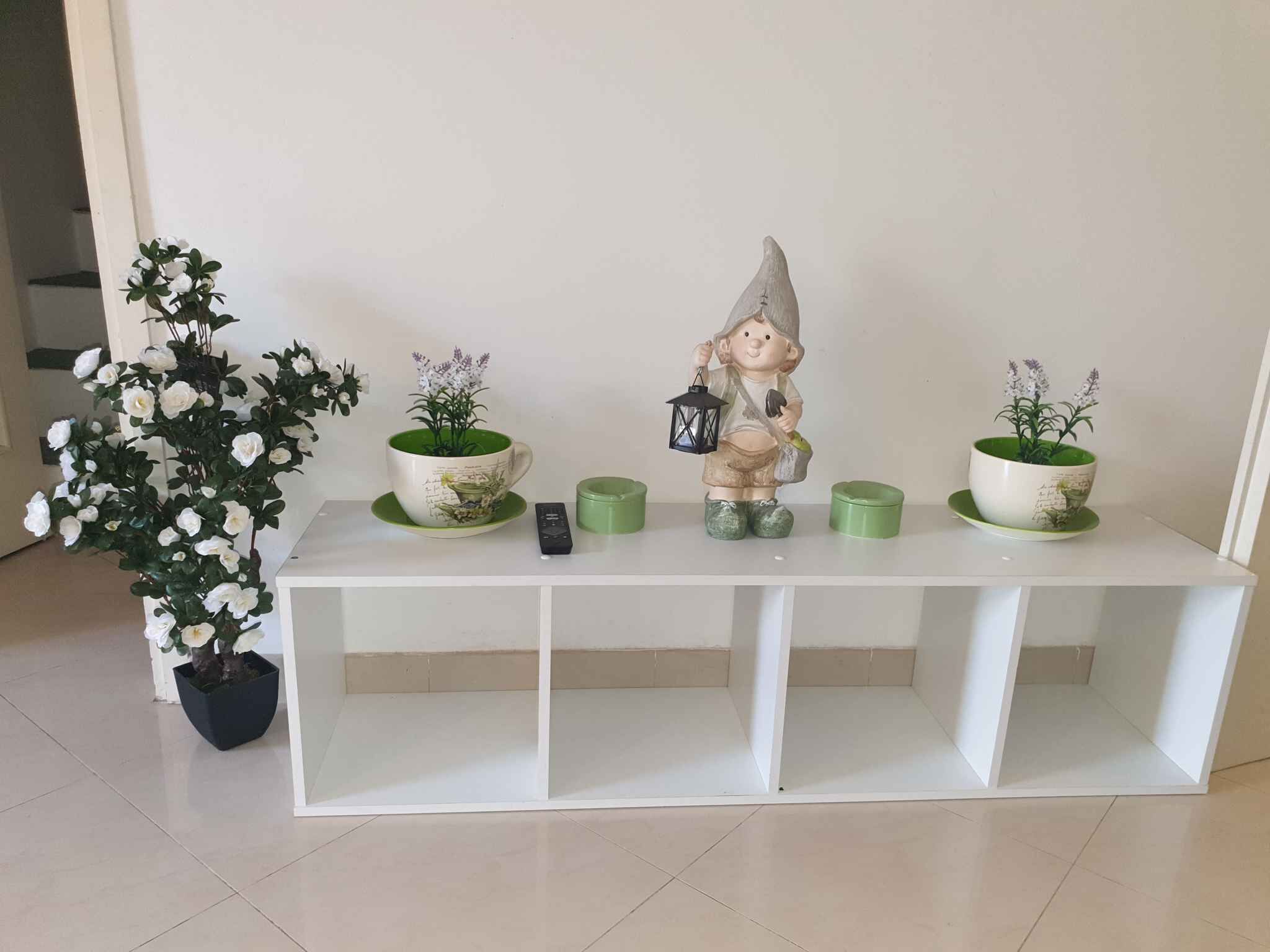 A white console table with three green potted plants and a figurine.