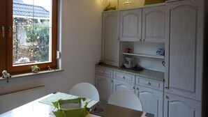 A kitchen with white cabinets, a window with a view of the outside, and a table with chairs. - Moni's Surfhaus - double room 1 (Rechlin)