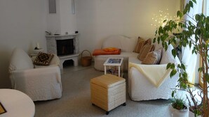 A cozy living room with a fireplace, two white sofas, a small table, and a potted plant. - Moni's Surfhaus - double room 1 (Rechlin)