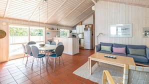 A spacious living area with a dining table, chairs, a sofa, and a kitchen in the background. - Stunning home in Nexø with kitchen (Nexø)