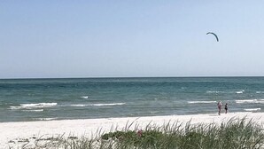 A beach with a clear sky, a person flying a kite, and the ocean in the background. - Stunning home in Nexø with kitchen (Nexø)