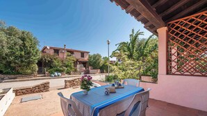 Une terrasse avec une table dressée pour le repas, entourée d’une pergola en bois et d’une clôture à treillis.