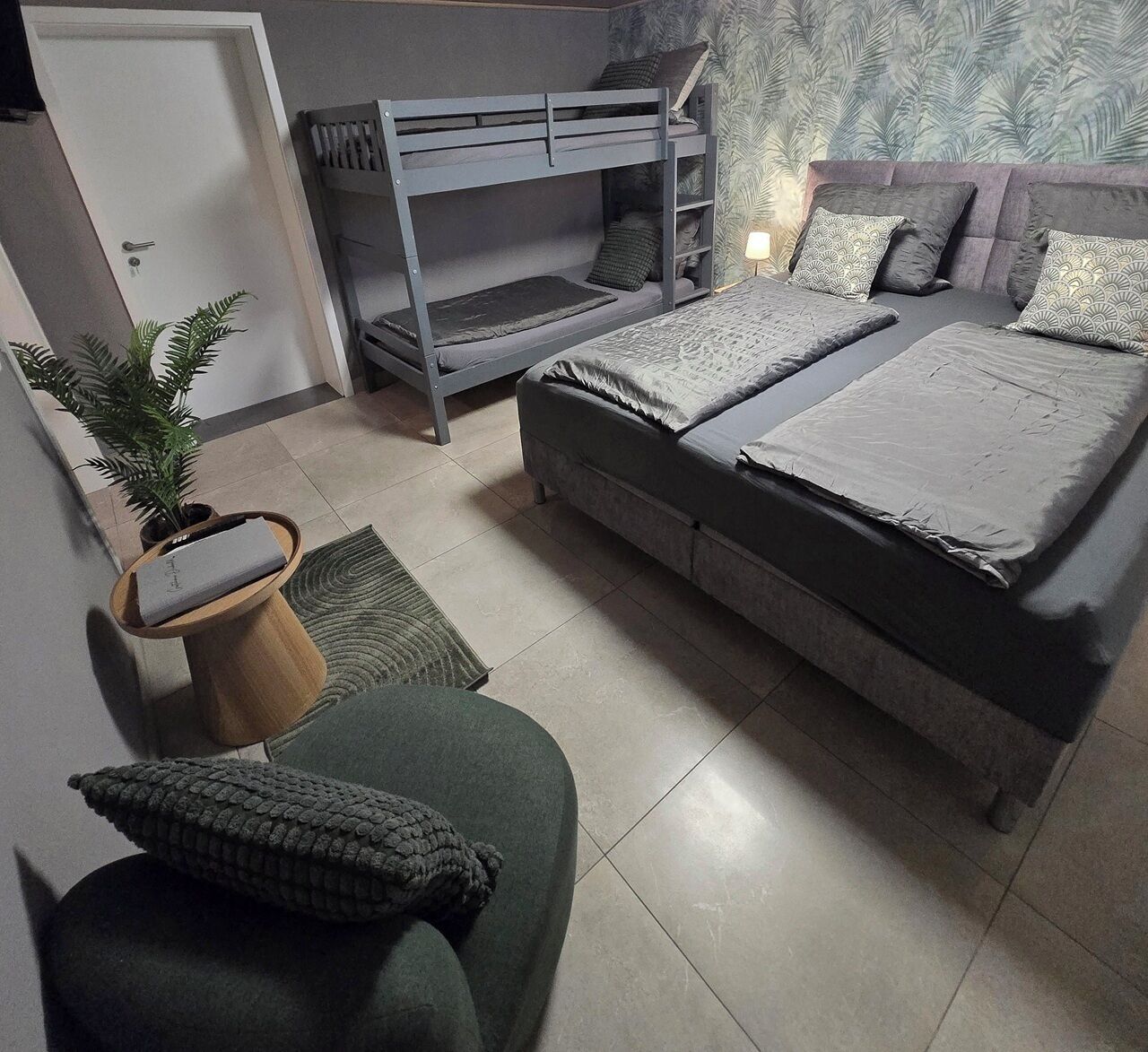 A bedroom with a bunk bed, a sofa, and a potted plant.