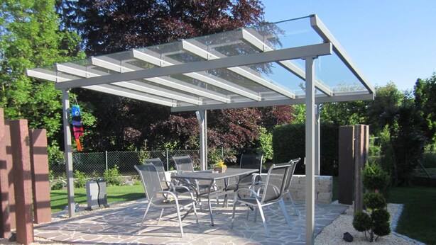 An outdoor patio with a pergola, stone flooring, and a table with chairs. - Gästehaus Alwin Diebold (Rust)