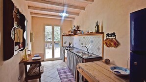Una cocina con techo de madera, salpicadero de azulejos, un lavabo y una estufa. Hay una ventana con vista a árboles.