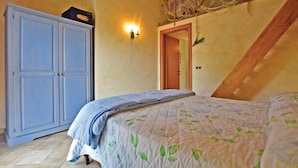 Un dormitorio con cama, armario y una lámpara de pared.
