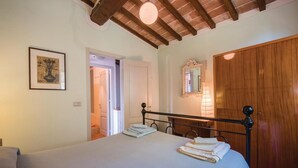 Un dormitorio con una cama, una puerta de madera, un espejo y un cuadro enmarcado en la pared.