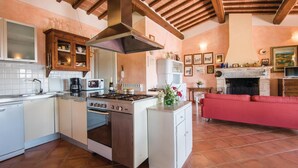 Cocina con isla central, estufa y microondas. En la sala de estar hay un sofá rojo y una chimenea.