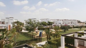 Una zona residencial moderna con edificios blancos, céspedes verdes y palmeras.
