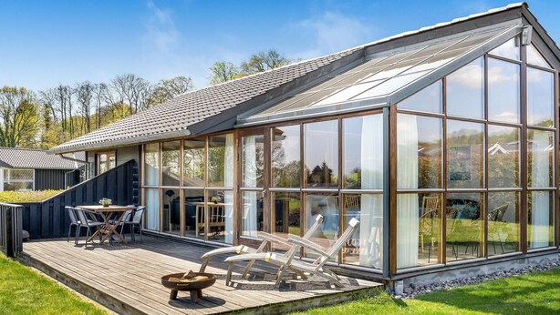 A modern glass house with a wooden deck and outdoor furniture. - 2 bedroom stunning home in Sjølund (Sjølund)