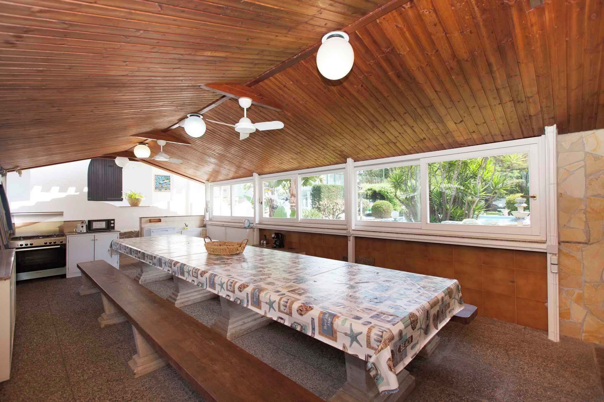 Une cuisine avec une longue table, un plafond en bois et de grandes fenêtres.