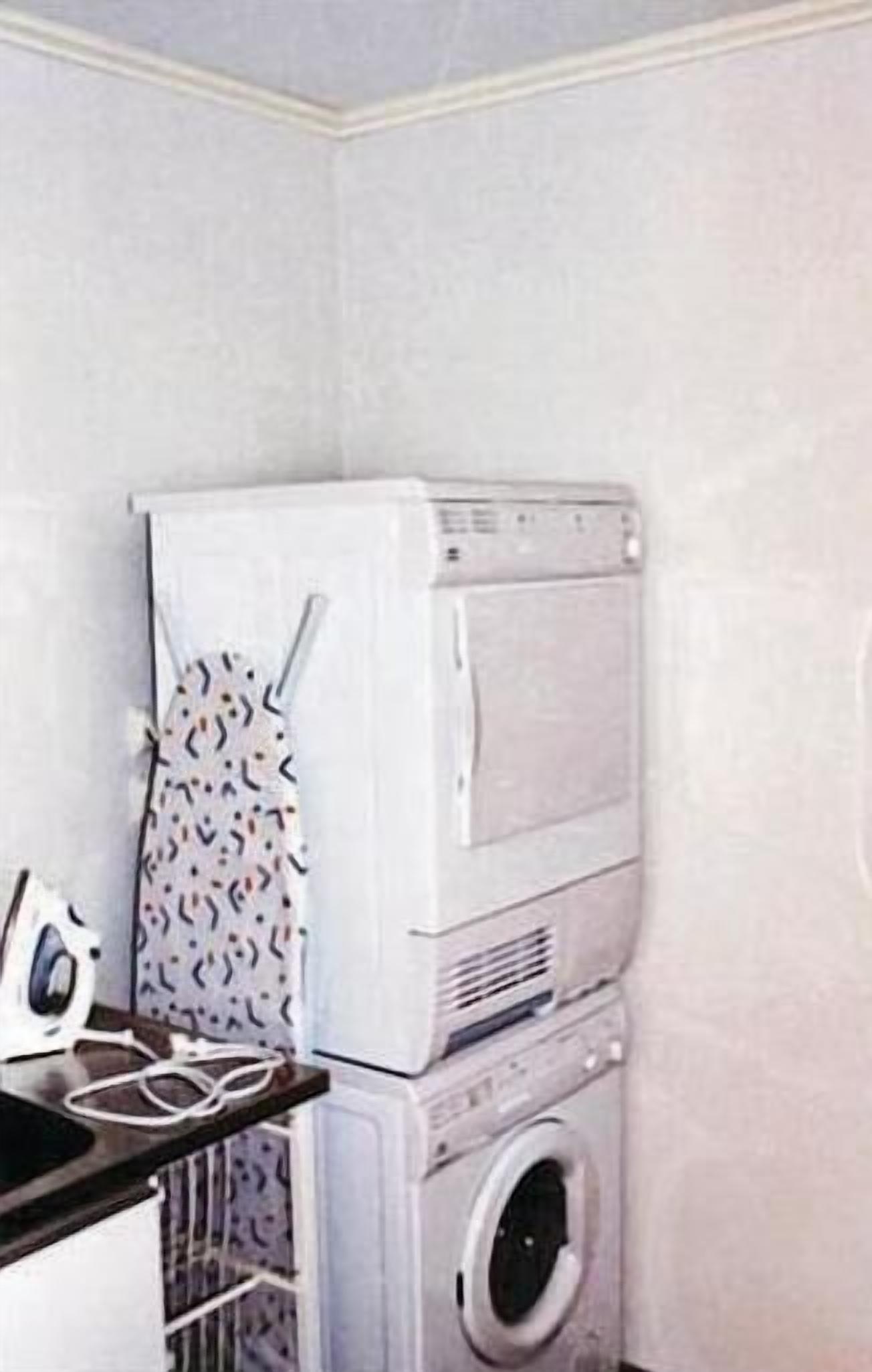 A laundry room with stacked appliances including a dryer and a washing machine.