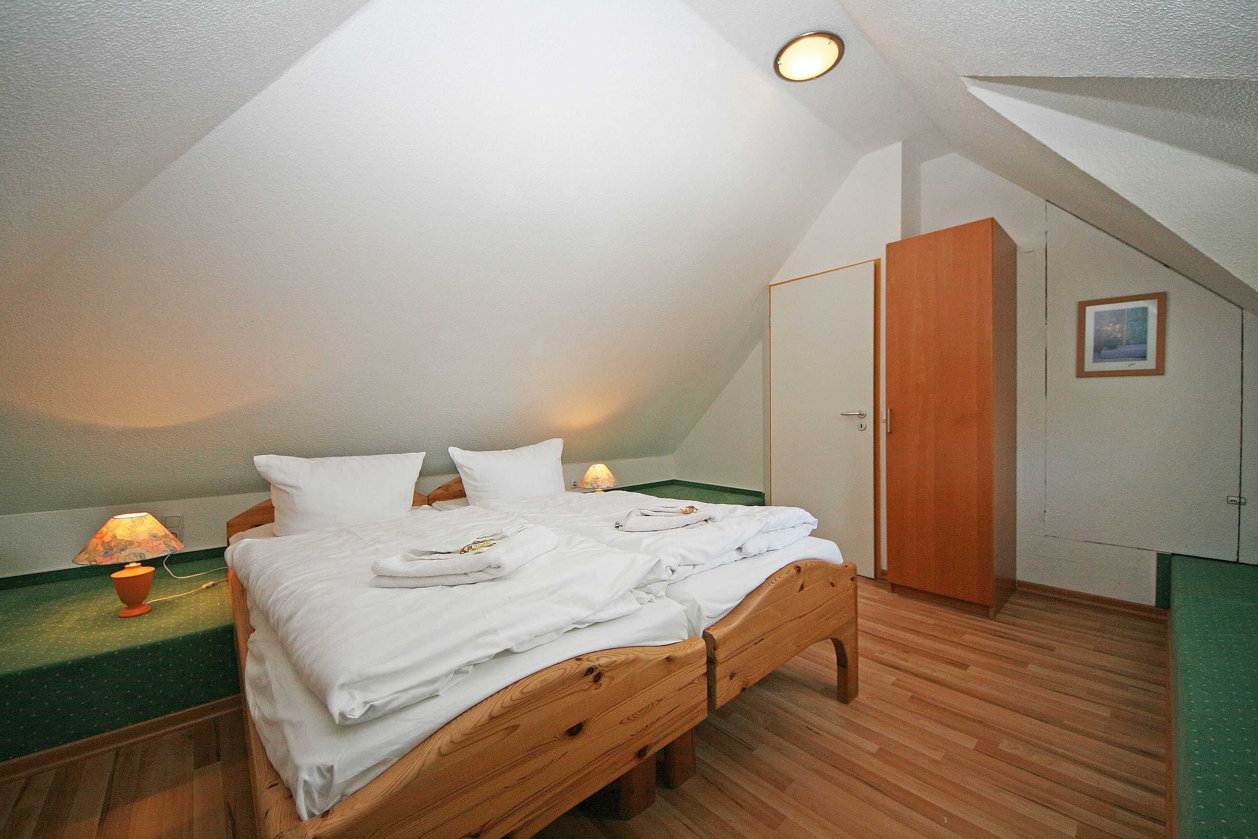 Un dormitorio con una cama de madera, una mesita de noche con lámpara y un armario.