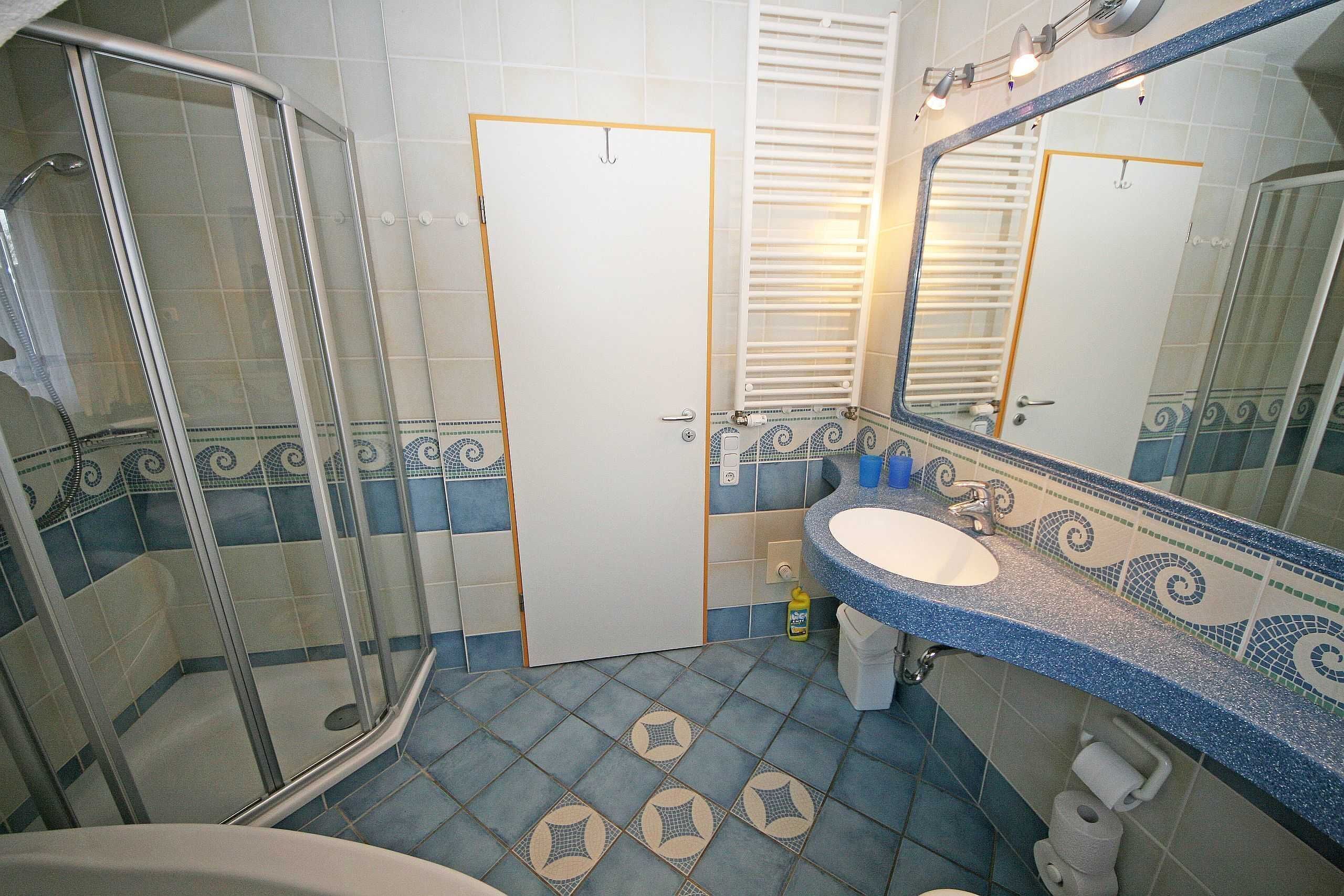 Ein Badezimmer mit Dusche, Waschbecken, Toilette und Spiegel.