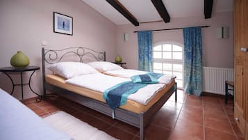 Une chambre à coucher avec un lit, une fenêtre avec des rideaux, un radiateur et une armoire en bois.