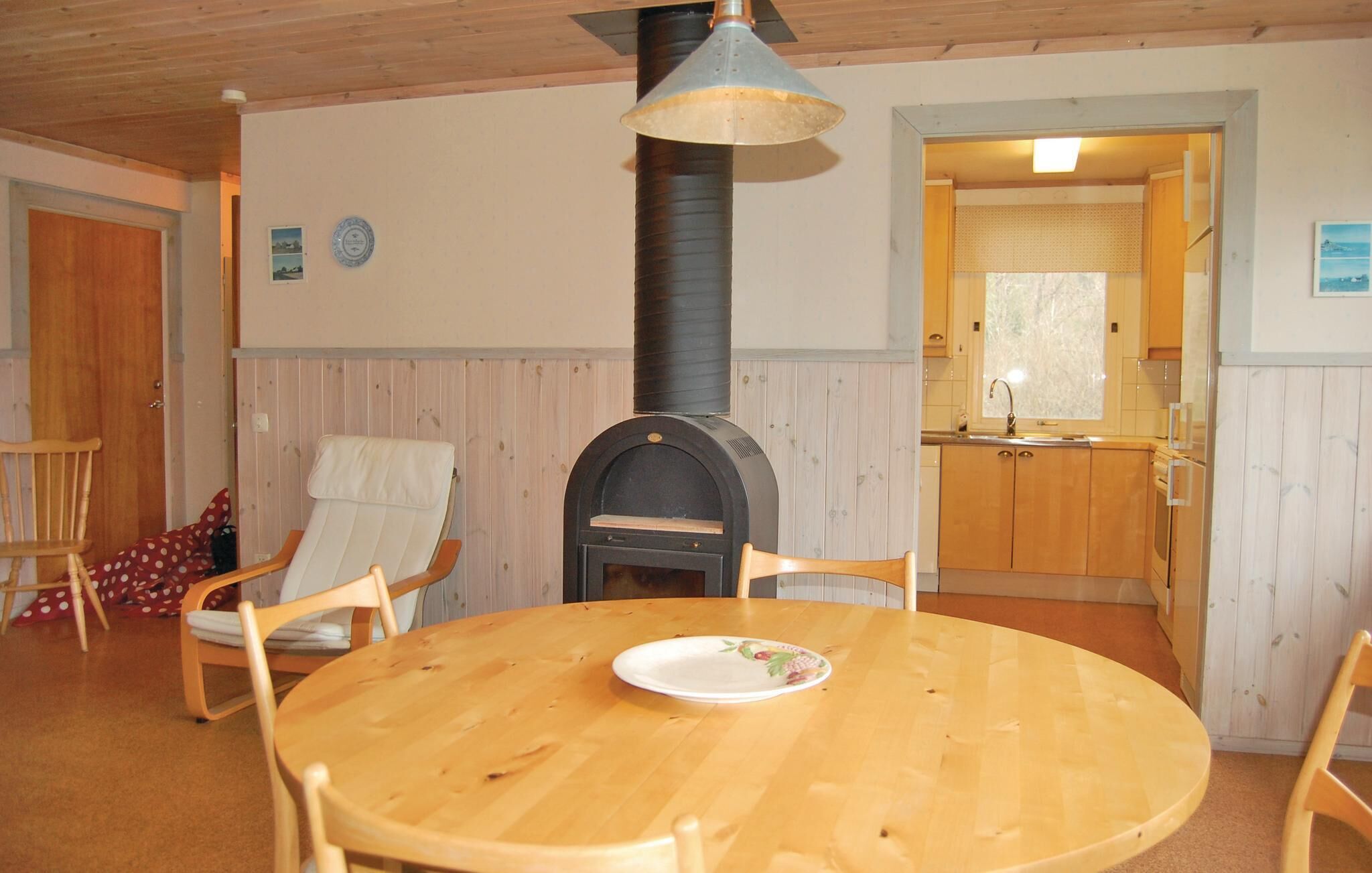 A cozy room with a wooden table, two chairs, a fireplace, and a kitchen area.