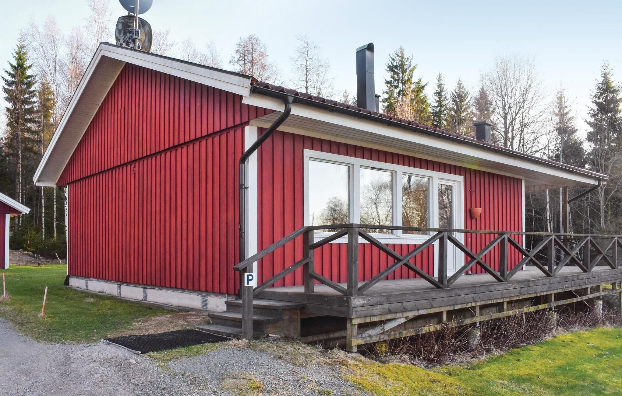 A red building with a white door and windows, a chimney, and a wooden deck.