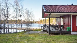A lakeside cabin with a covered porch, outdoor seating, and a view of the lake.