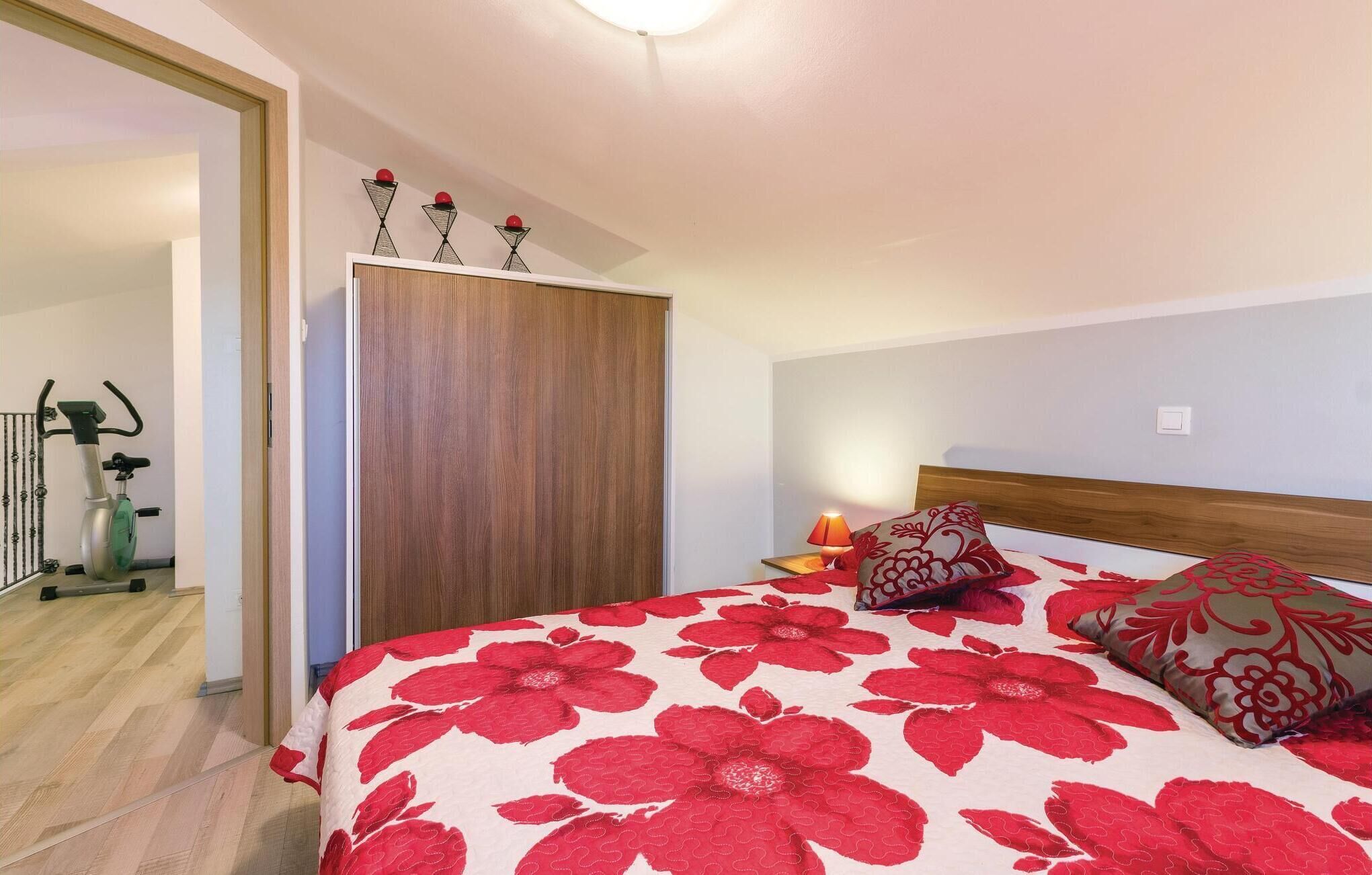 A bedroom with a large bed, a wooden wardrobe, and a nightstand with a lamp.