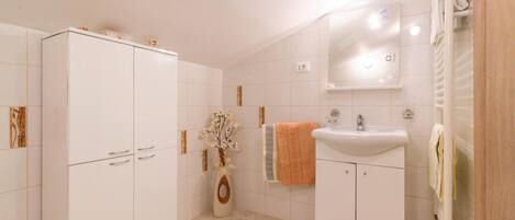 Un baño con un mueble blanco, un lavabo y un espejo.