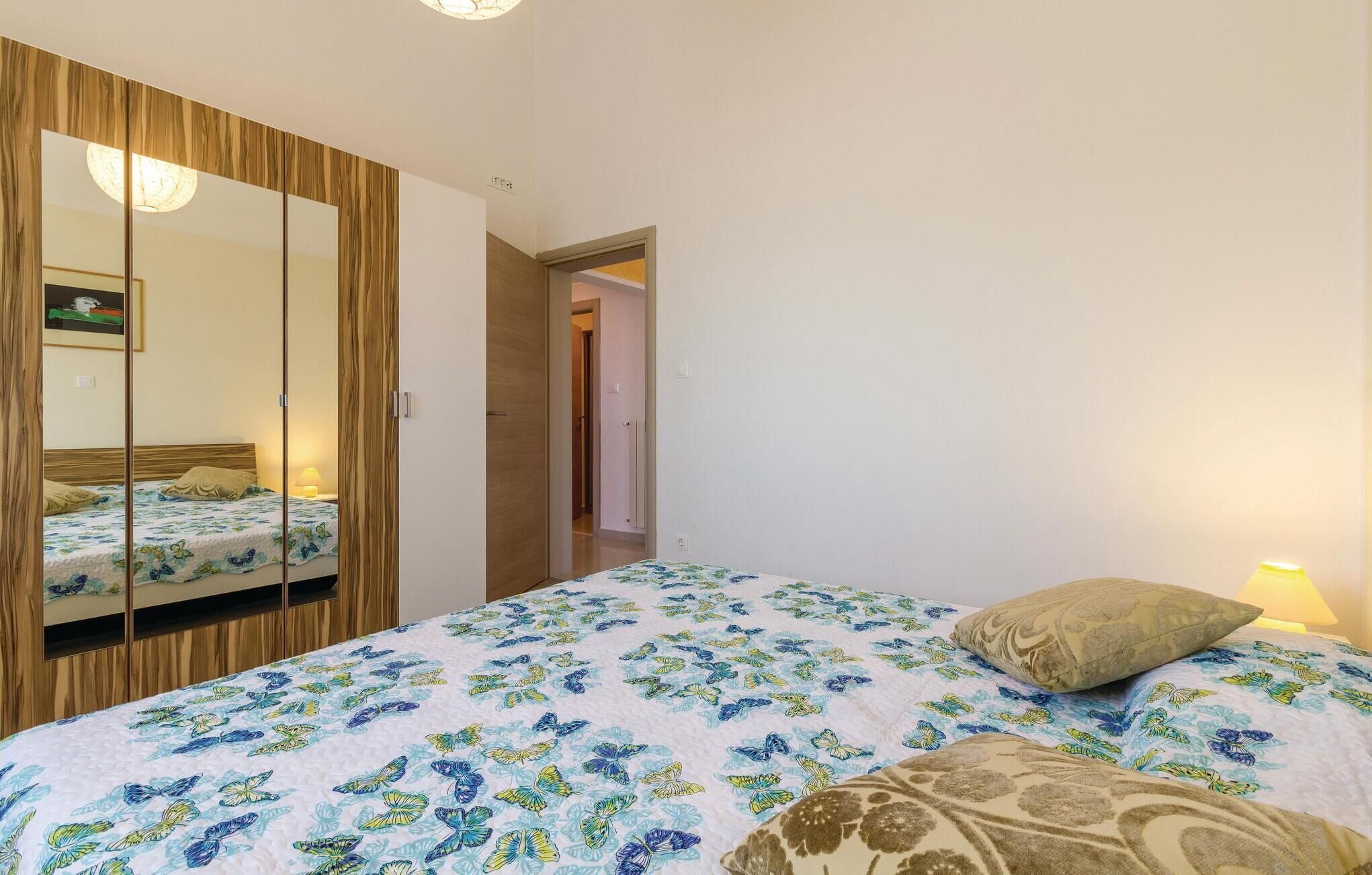Una camera da letto con un letto, uno specchio e una porta che dà su un'altra stanza.