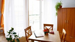 A dining area with a table, chairs, a potted plant, and a view through a window. - Apartment 2 - 32sqm (2 persons), balcony - Weichaer Hof FBS Sonja Fritsch & (Weißenberg)
