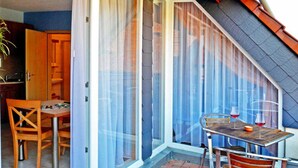 A dining area with a table and chairs, a sliding glass door, and a view of the outside. - Apartment 2 - 32sqm (2 persons), balcony - Weichaer Hof FBS Sonja Fritsch & (Weißenberg)