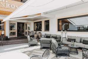 Une terrasse d’hôtel avec des meubles en osier, un canapé et une table.