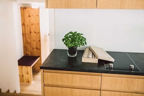 A kitchen with a black countertop, wooden cabinets, a potted plant, and a woven basket.