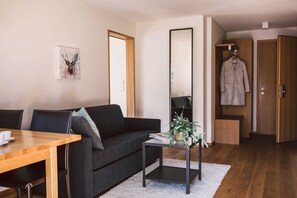 Una sala de estar moderna con un sofá, una mesa de centro, una mesa de comedor, un espejo y un armario.