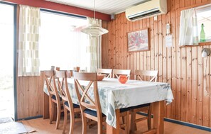 Un comedor con una mesa y sillas de madera, una lámpara colgante y una ventana con cortinas.