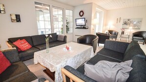 Una sala de estar acogedora con sofá, sillones, una mesa de centro y televisor.