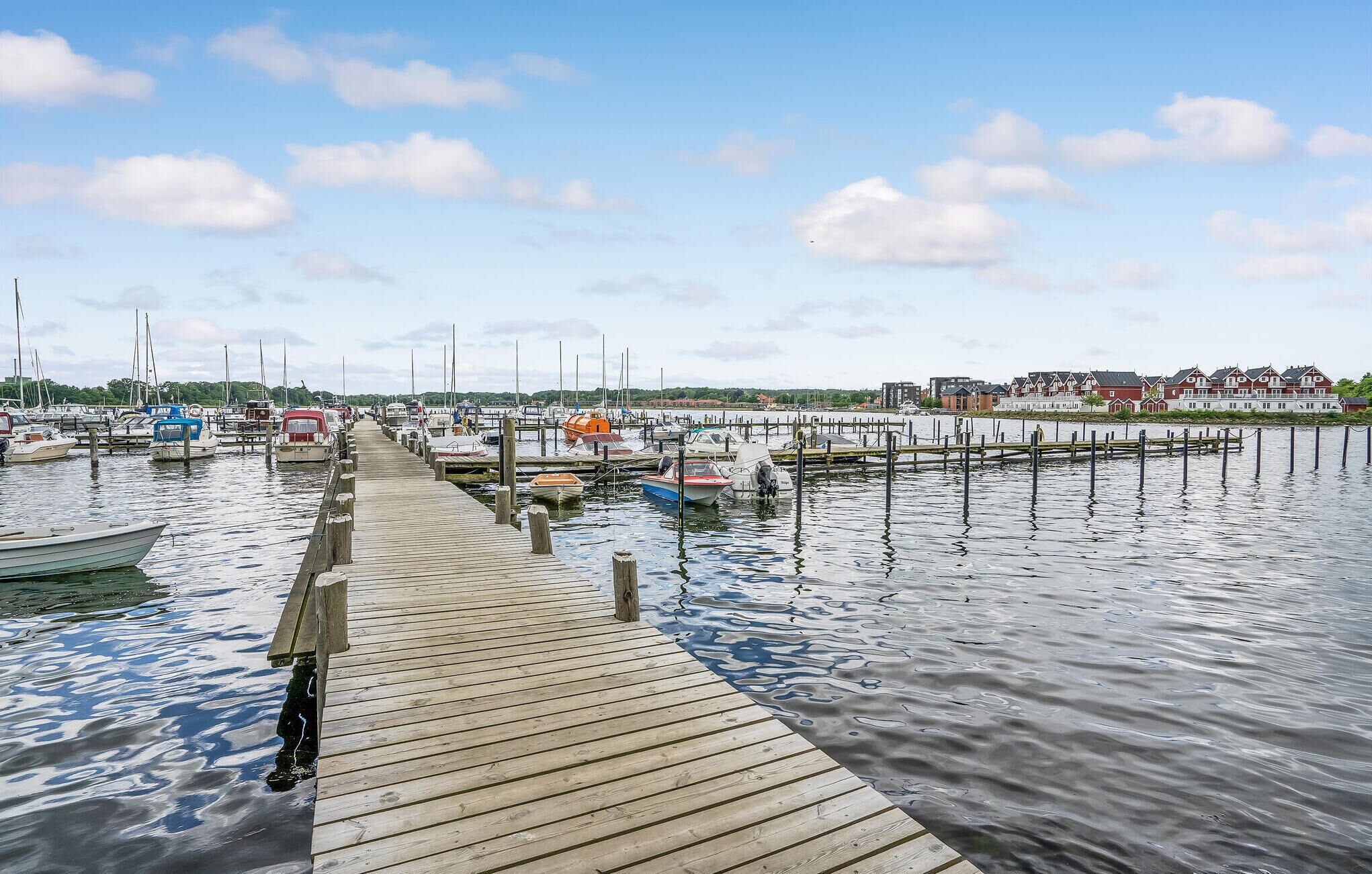 En træbrygge der fører til en lysthavn med forskellige både fortøjet.