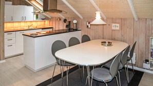 A modern kitchen with white cabinets, a central island, and a dining area with a round table and chairs. - 3 bedroom gorgeous home in Oksbøl (Oksbøl)