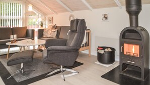 A cozy living room with a modern fireplace, a sofa, a coffee table, and a chair. - 3 bedroom gorgeous home in Oksbøl (Oksbøl)