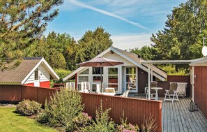 Une cabane dotée d’un patio, d’un espace salon couvert et d’un jardin clôturé.