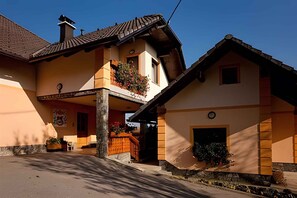 Ein zweistöckiges Gebäude mit Balkon, kleiner Veranda und Steinbasis.