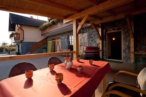 An outdoor dining area with a red tablecloth, wooden chairs, and a stone wall backdrop.