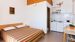 Ein Schlafzimmer mit Bett, Nachttischlampe und einer Küchenzeile inklusive Schränke und Spüle.