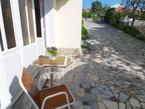 Un espace extérieur aménagé avec une table et des chaises, un pot de fleurs et un chemin pavé de pierres.