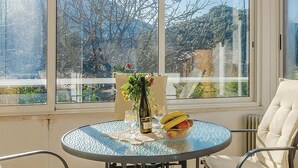 A round glass table with a bottle of wine, a vase with flowers, and a bowl of fruit. - Lovely apartment in Zuljana with house sea view (Zuljana)