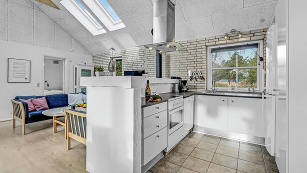 Una cocina moderna con gabinetes blancos, un ventanal grande y un tragaluz.