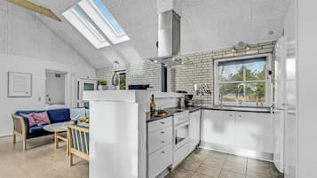 Une cuisine moderne avec des meubles blancs, une grande fenêtre et un puits de lumière.