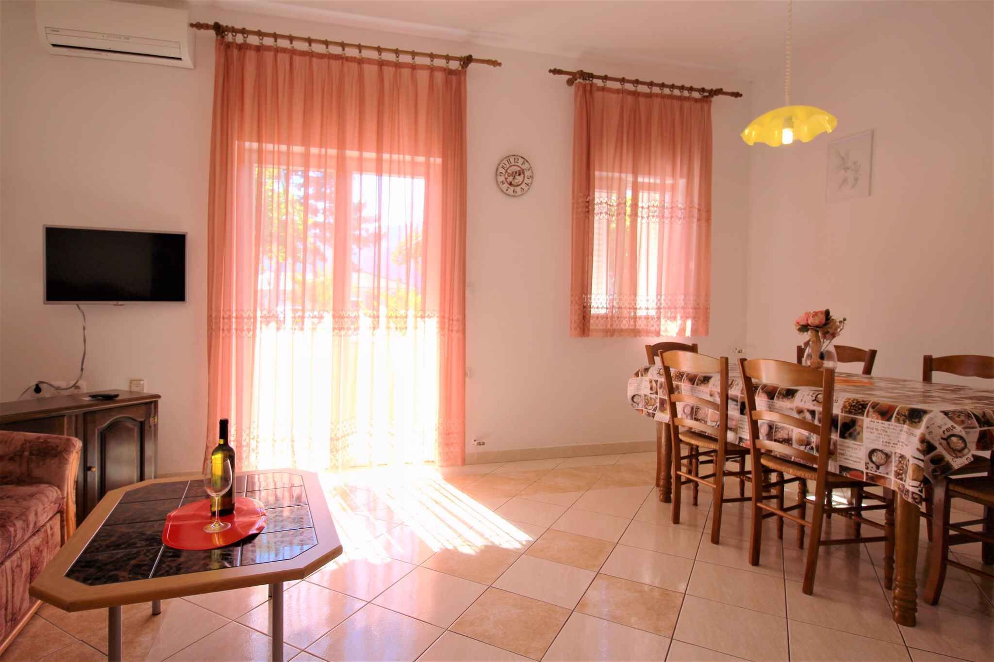 A living room with a TV, a table with a wine bottle, and a dining area with a table set for four.