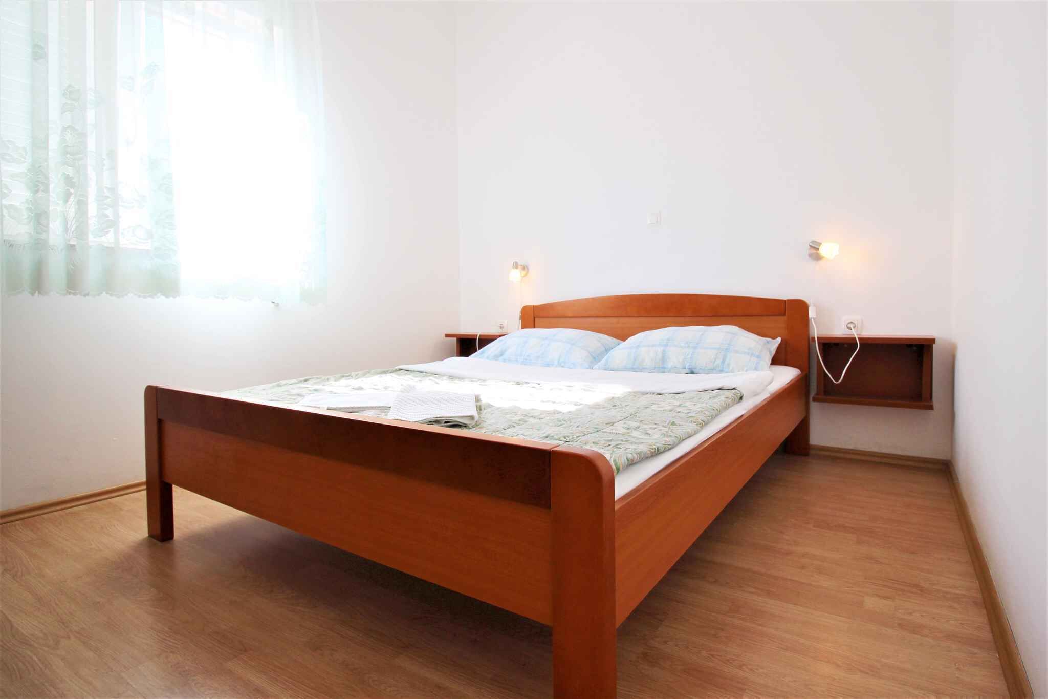 Una cama individual con estructura de madera, una mesita de noche y un aplique de pared.