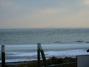 Une vue sur la côte, avec un navire à l’horizon, une clôture en bois et une balustrade.