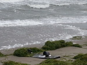A beach with waves, seaweed, and a pair of headphones on a mat. - Apartment beach runner - beach house bay center (Scharbeutz)