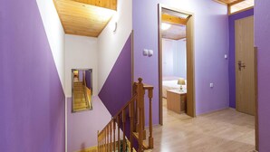 A hallway with purple walls, a wooden staircase, and a door leading to a bathroom. - Awesome home in Gajana (Gajana)